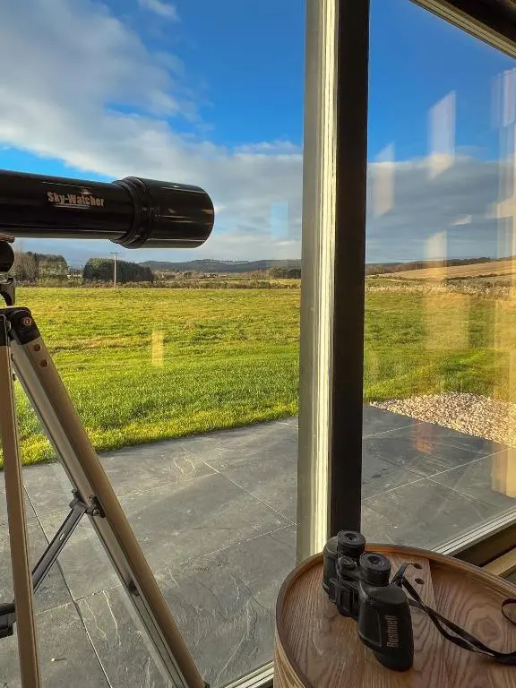 a camera in front of a window with a view of a field at Tillyfruskie Farm Holiday Cabin, Finzean in Banchory