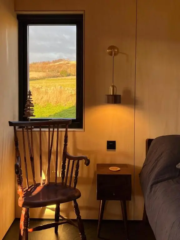 a bedroom with a chair and a window at Tillyfruskie Farm Holiday Cabin, Finzean in Banchory