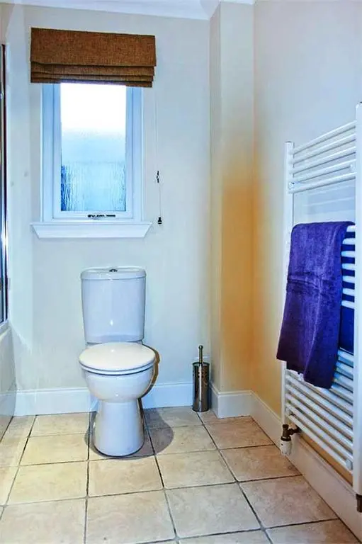 a bathroom with a toilet and a window and blue towels at Hillview House Hostel Inverness in Inverness