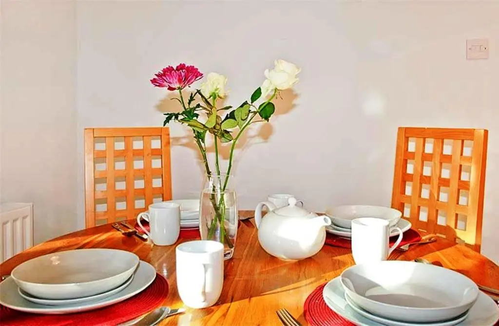 a wooden table with plates and a vase of flowers at Hillview House Hostel Inverness in Inverness