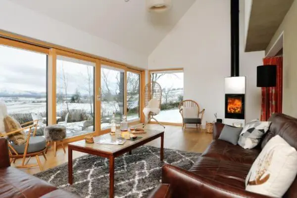 a living room with a couch and a table at Beautiful Lodge with hot tub & panoramic views in Boat of Garten