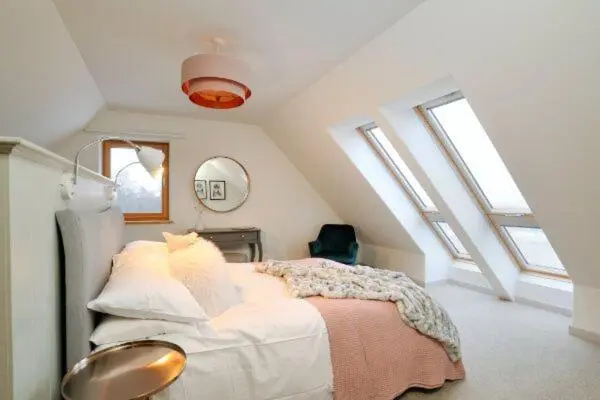 a bedroom with a bed in a attic with windows at Beautiful Lodge with hot tub & panoramic views in Boat of Garten