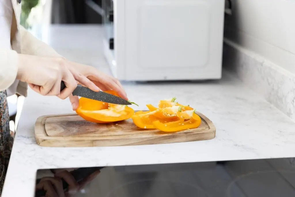 a person cutting up an orange on a cutting board at Byrnside Lodge in Latheron