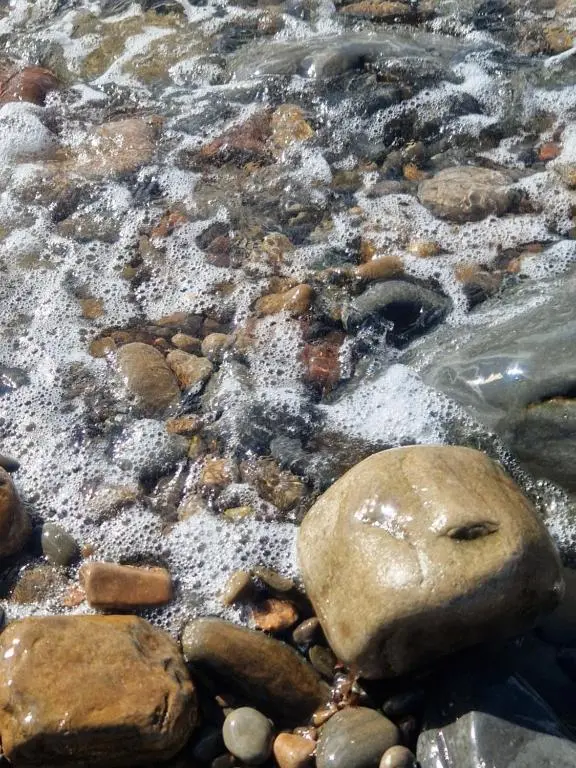 a close up of rocks and water on a beach at Byrnside Lodge in Latheron