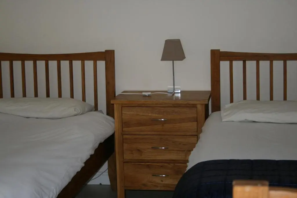 a bedroom with two beds and a night stand with a lamp at BCC Loch Ness Hostel in Bearnock