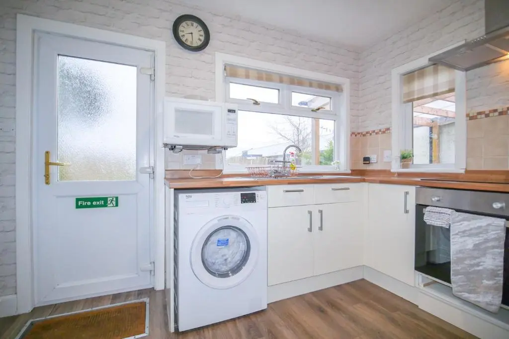 a kitchen with a washing machine and a clock on the wall at Lochlash 3 Bedroom House Inverness in Inverness