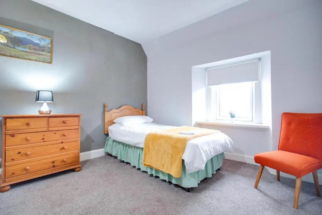 a bedroom with a bed and a dresser and a window at Novar 4 Bedroom House Alness in Inverness