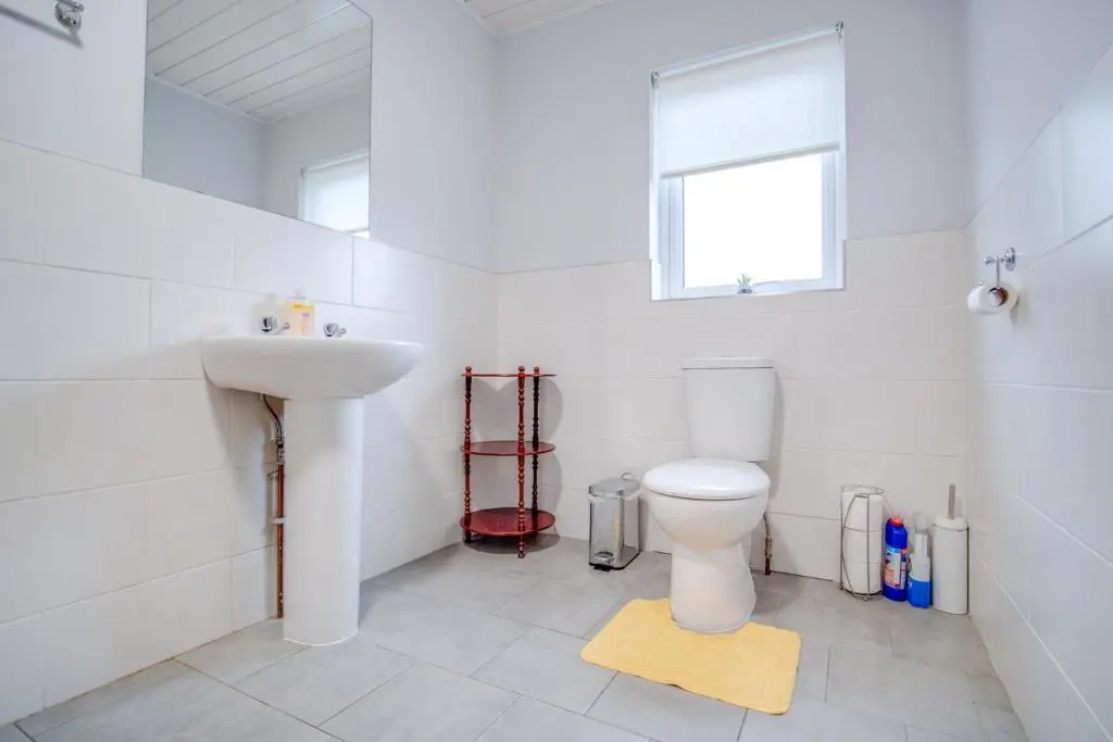 a white bathroom with a toilet and a sink at Novar 4 Bedroom House Alness in Inverness