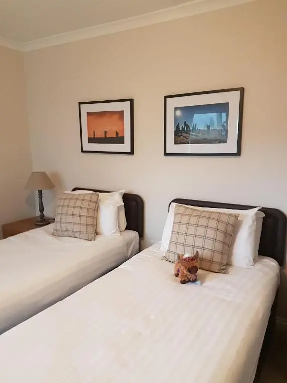 a teddy bear sitting on a bed in a bedroom at Loch Ness Guest House in Fort Augustus
