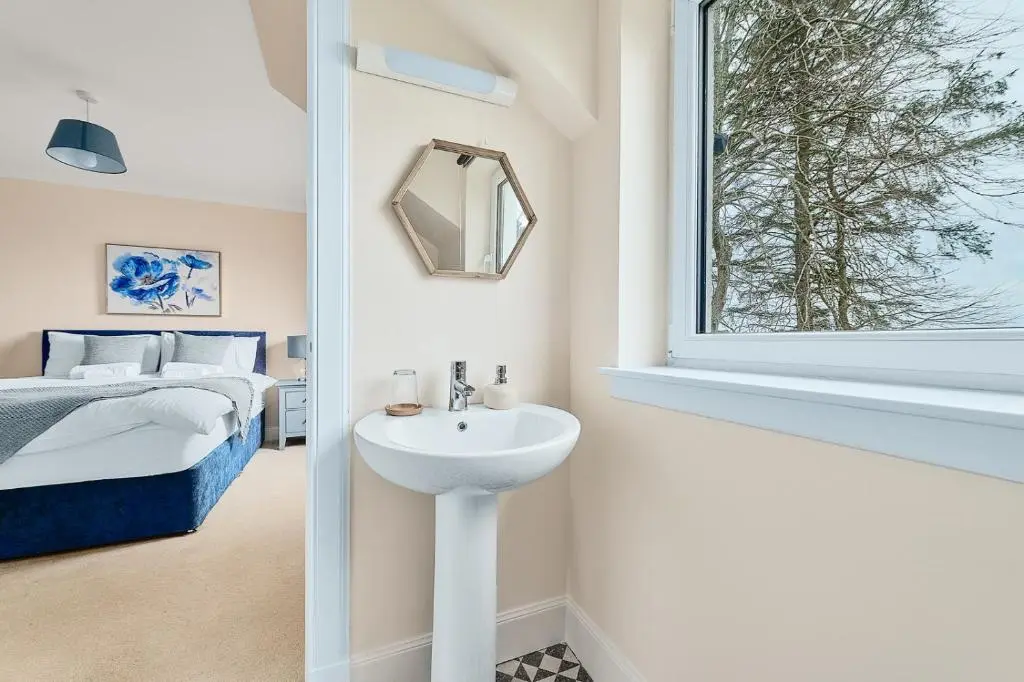 a bathroom with a sink and a bed and a window at Kinkell House Rooms in Cononbridge