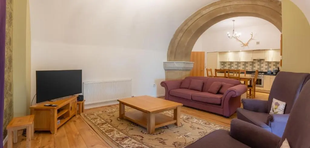 a living room with two purple couches and a tv at Abbey Church Upper North Aisle Luxury Self Catering 2 bedroom Apartments in Fort Augustus