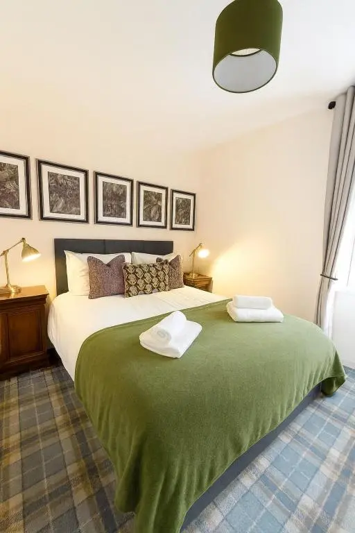 a bedroom with a green bed with two towels on it at Bed on the Brae in Inverness