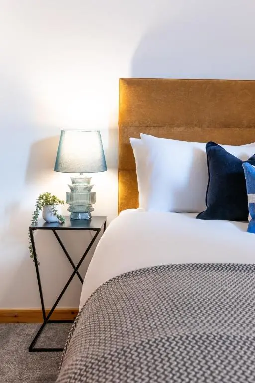 a bed with a night stand with a lamp on it at Ness Station in Inverness