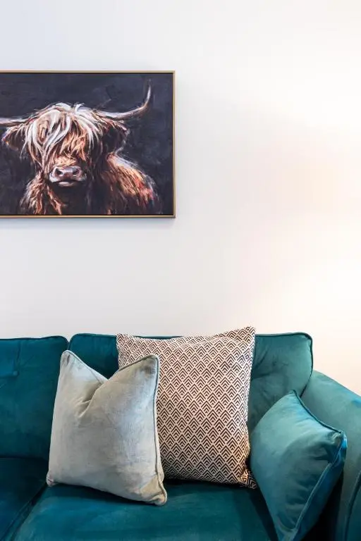 a couch with pillows and a picture of a cow at Ness Station in Inverness
