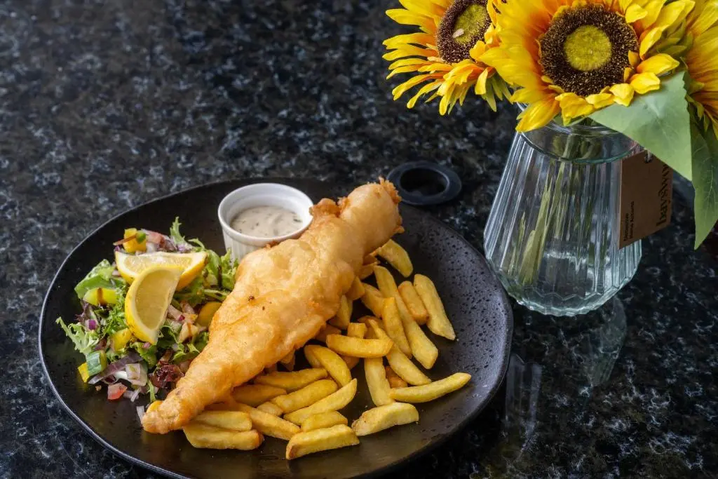 a plate of food with a fish and french fries at Loch Ness Drumnadrochit Hotel in Drumnadrochit