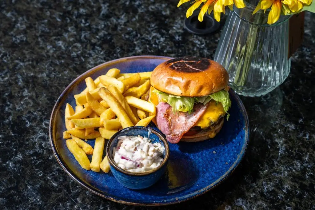 a blue plate with a sandwich and french fries at Loch Ness Drumnadrochit Hotel in Drumnadrochit