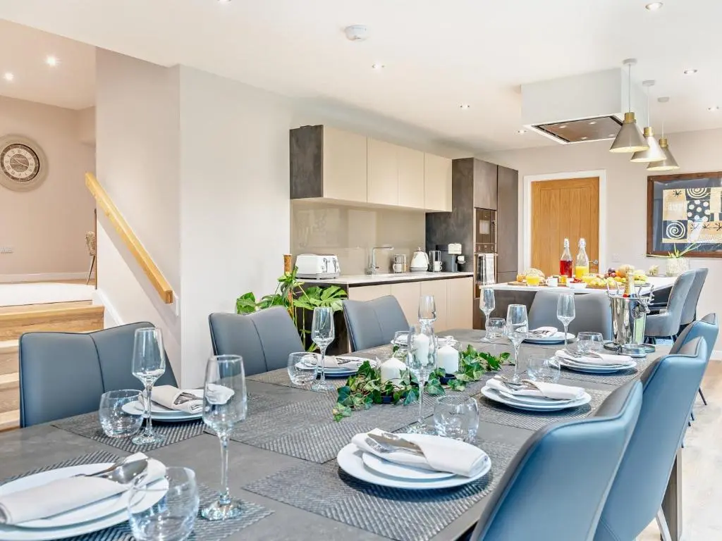 a dining room with a long table and blue chairs at 4 Bed in Dyce 93914 in Dyce