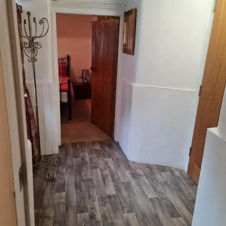 a hallway with a door and a wooden floor at Ness City Cottage - Attic Apartment in Inverness