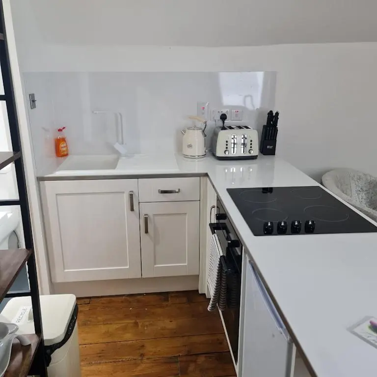 a kitchen with white cabinets and a stove top oven at Ness City Cottage - Attic Apartment in Inverness