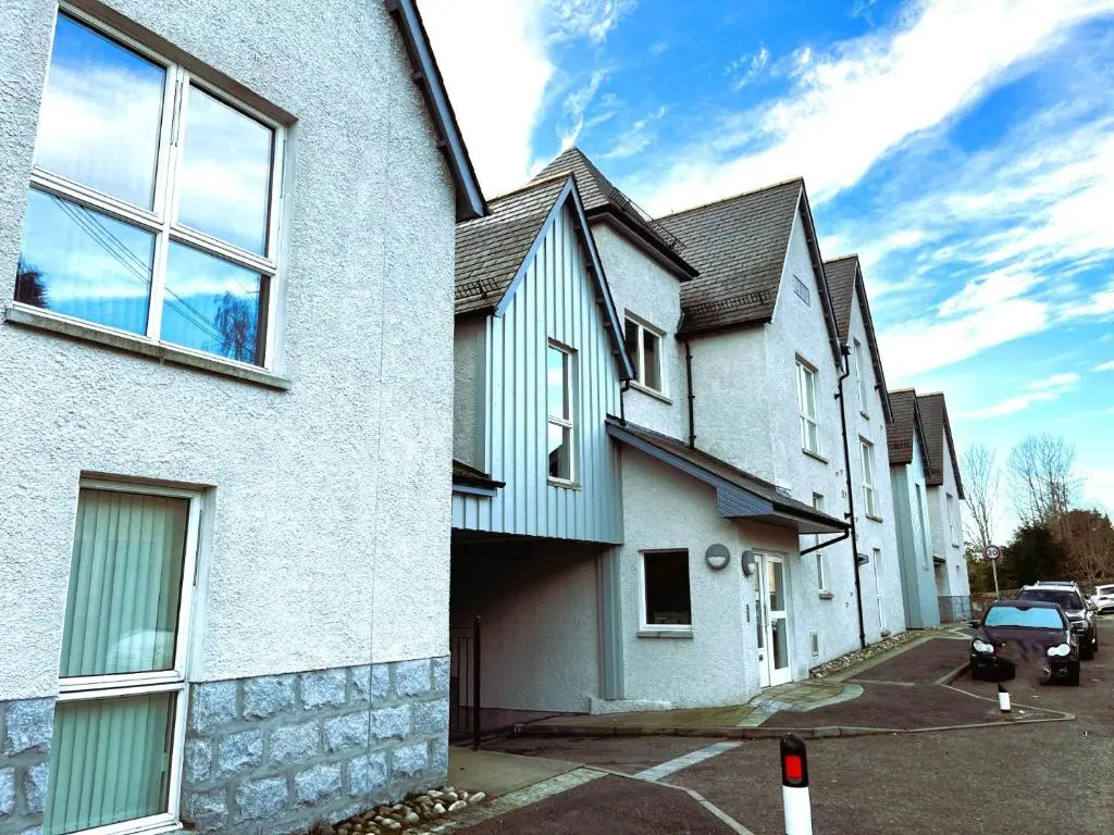 a white house with a car parked in a parking lot at Entire flat in Banchory, Aberdeenshire, Scotland in Banchory