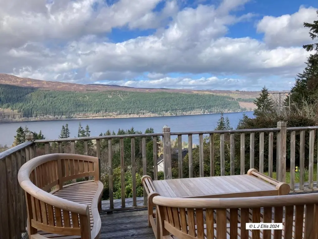 a deck with two chairs and a table and a lake at Foyers House in Foyers