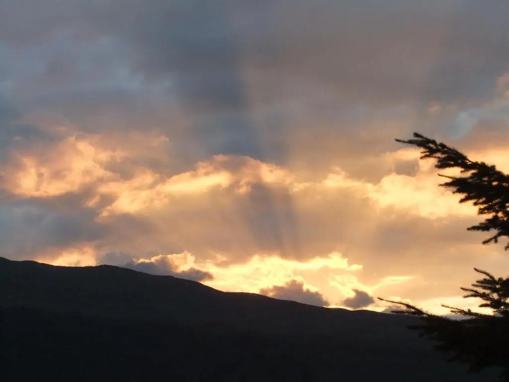 a sunset with the sun shining through the clouds at Foyers House in Foyers