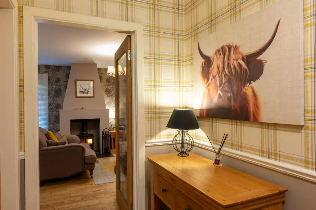 a living room with a painting of a cow on the wall at Abbey Holidays Loch Ness Luxury Self Catering 2 Bedroom Cottages in Fort Augustus