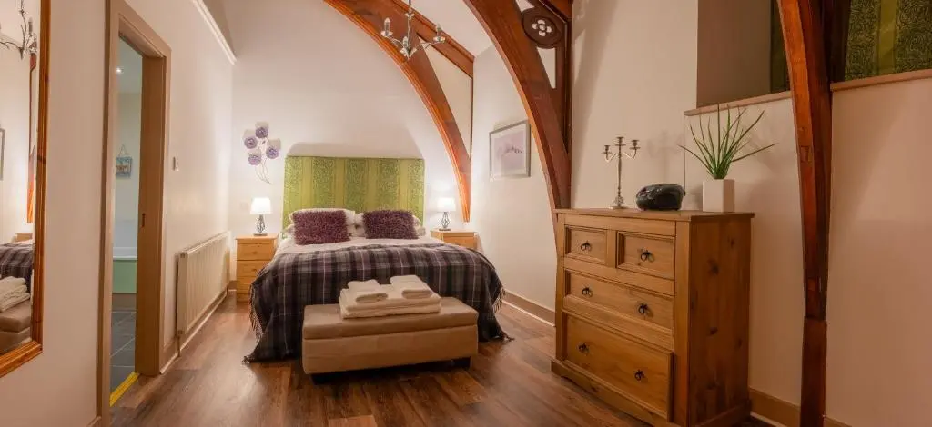 a bedroom with a bed and a dresser in it at The Caledonian 3 Bedroom Self Catering Apartment in historic Abbey in Fort Augustus