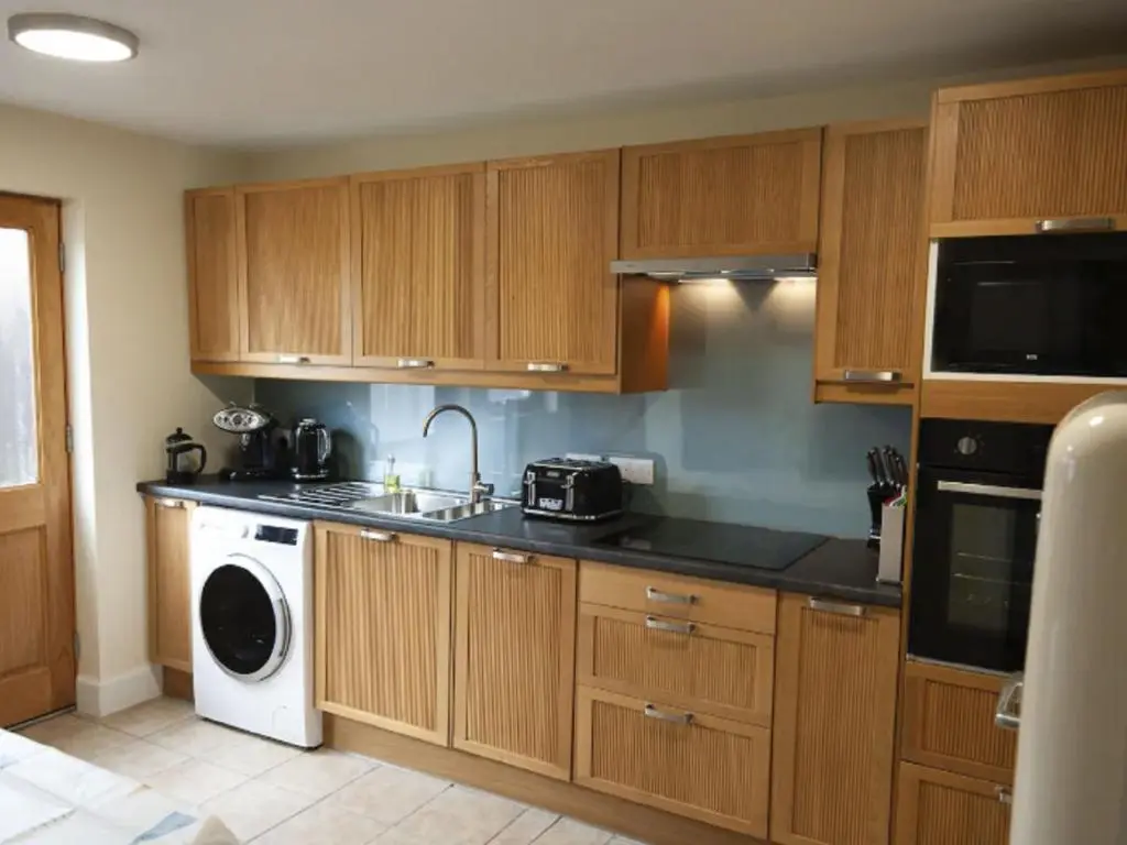 a kitchen with wooden cabinets and a washer and dryer at Holiday Home Oakdale House by Interhome in Drumnadrochit