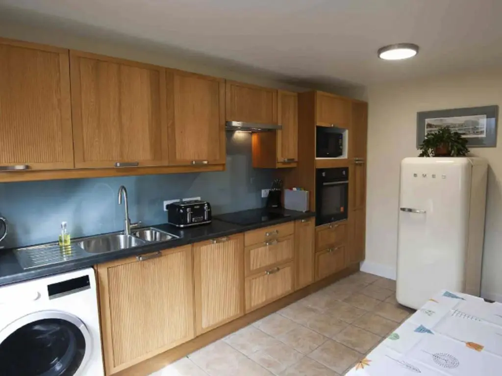 a kitchen with wooden cabinets and a white refrigerator at Holiday Home Oakdale House by Interhome in Drumnadrochit