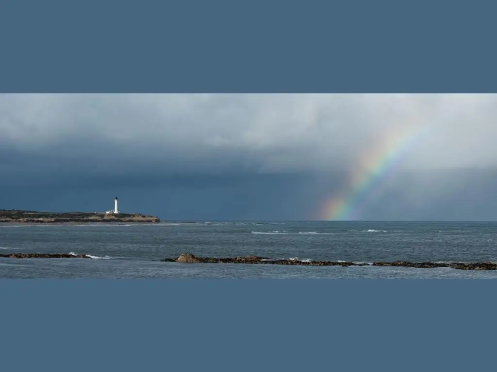 a rainbow over the ocean with a body of water at Apartment Harbour Nights Deluxe 7C by Interhome in Lossiemouth