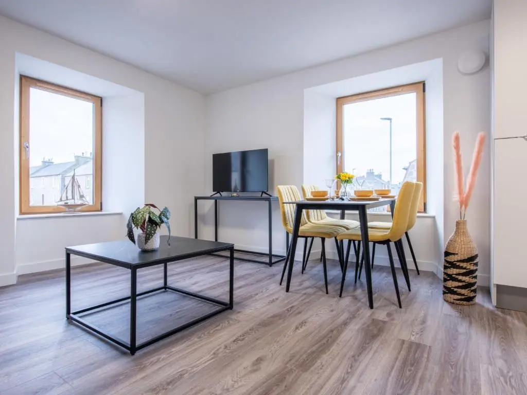 a living room with a table and chairs in a room at Apartment Harbour Nights Deluxe 7C by Interhome in Lossiemouth