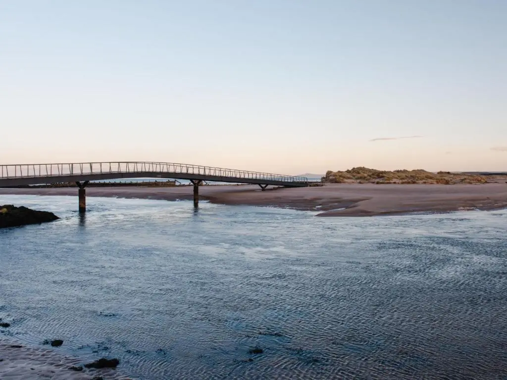 a bridge over a river next to a beach at Apartment Harbour Nights Deluxe Number 12 by Interhome in Lossiemouth
