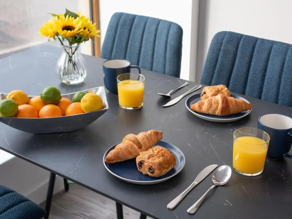 a table with plates of food and orange juice at Apartment Harbour Nights Deluxe Number 12 by Interhome in Lossiemouth
