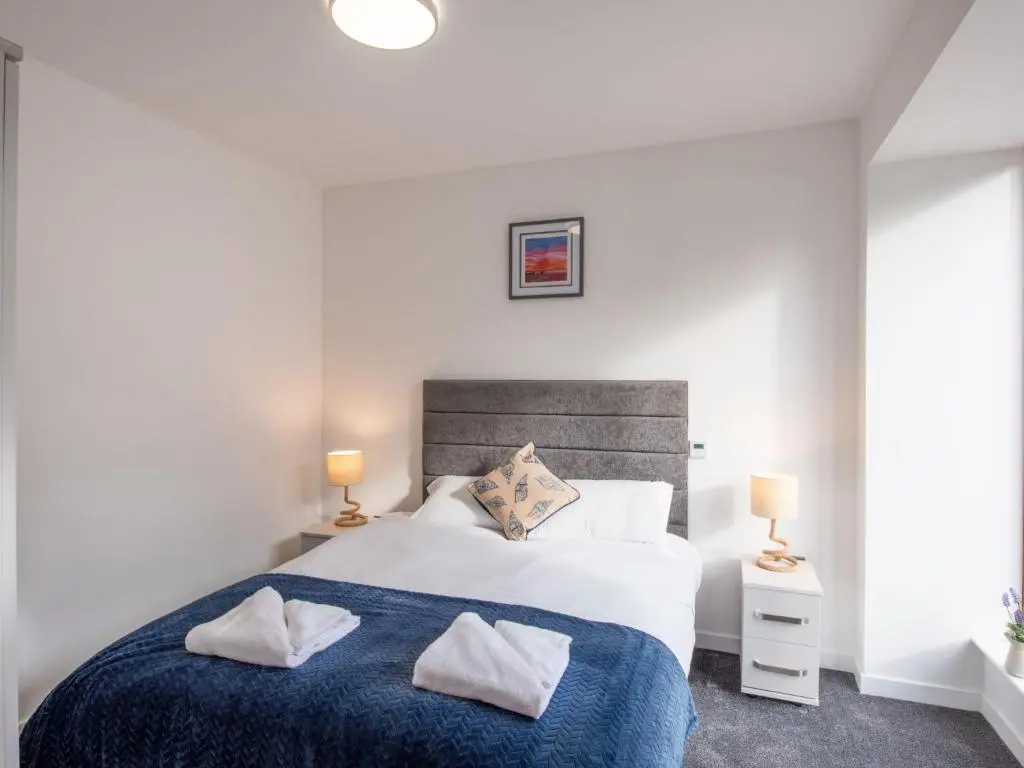 a bedroom with a large bed and two lamps at Apartment Harbour Nights Deluxe Number 12 by Interhome in Lossiemouth