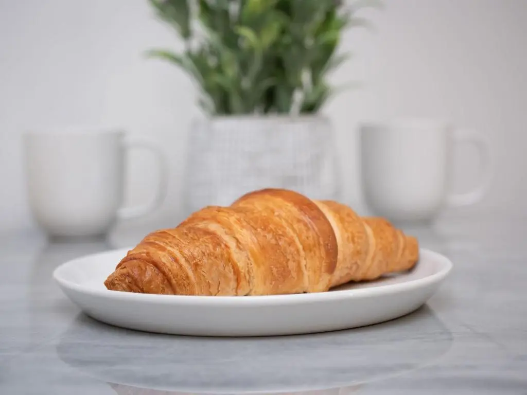 two croissants on a white plate on a table at Apartment Harbour Nights Deluxe 7A by Interhome in Lossiemouth