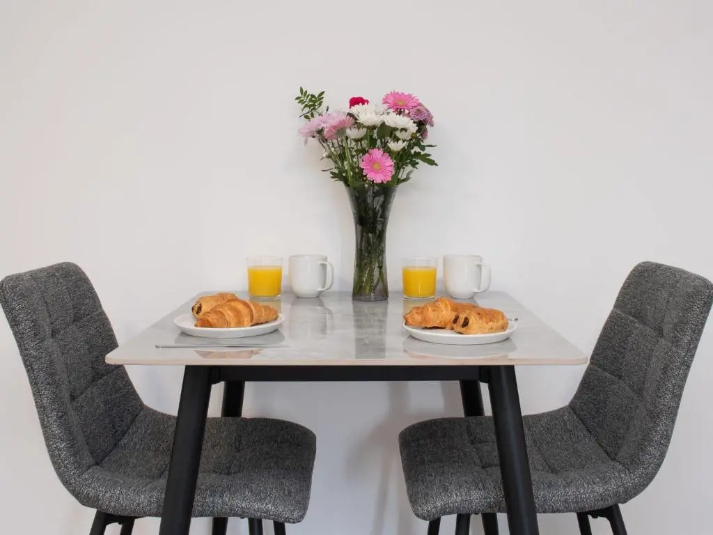 a table with two plates of pastries and a vase of flowers at Apartment Harbour Nights Deluxe 7A by Interhome in Lossiemouth
