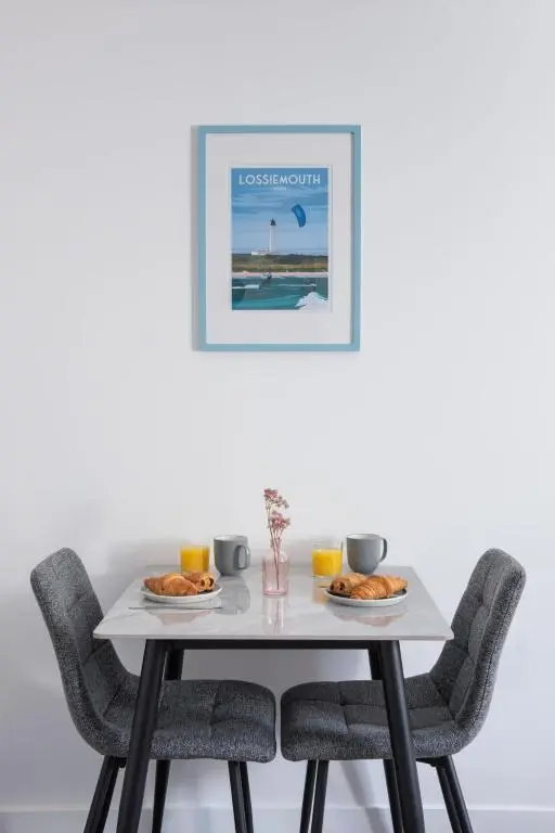 a white table with chairs and food on it at Apartment Harbour Nights Deluxe 7B by Interhome in Lossiemouth
