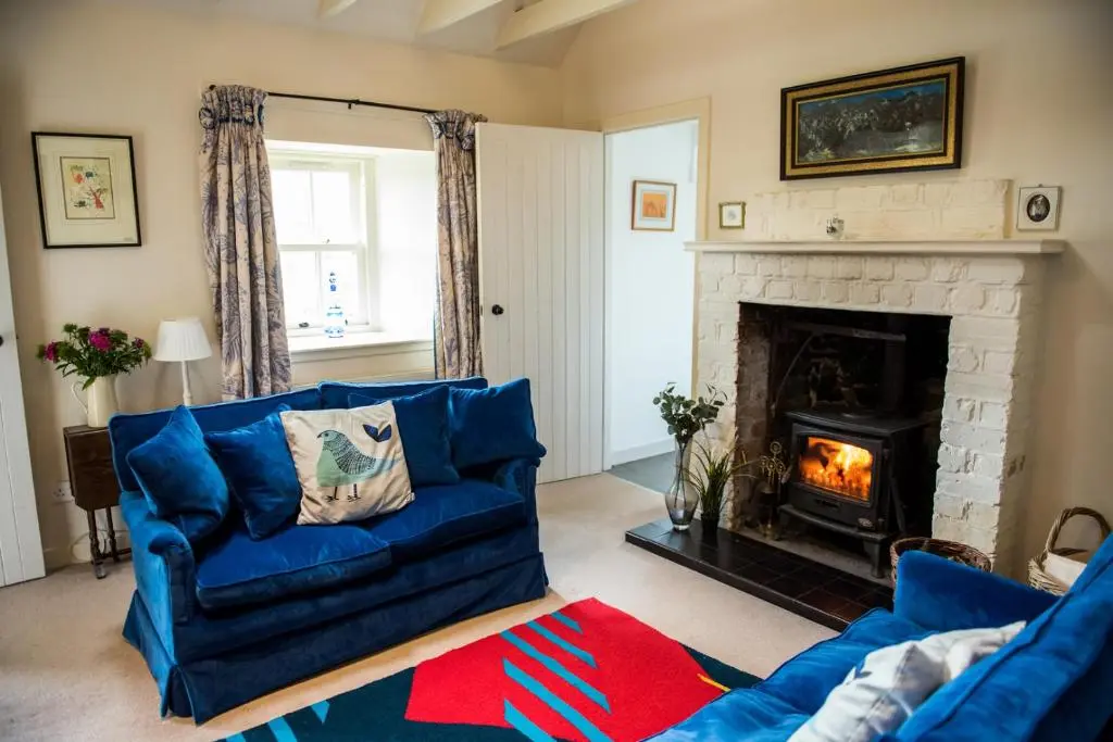 a living room with a blue couch and a fireplace at Colmeallie Bothy - Seasgair Lodges in Brechin
