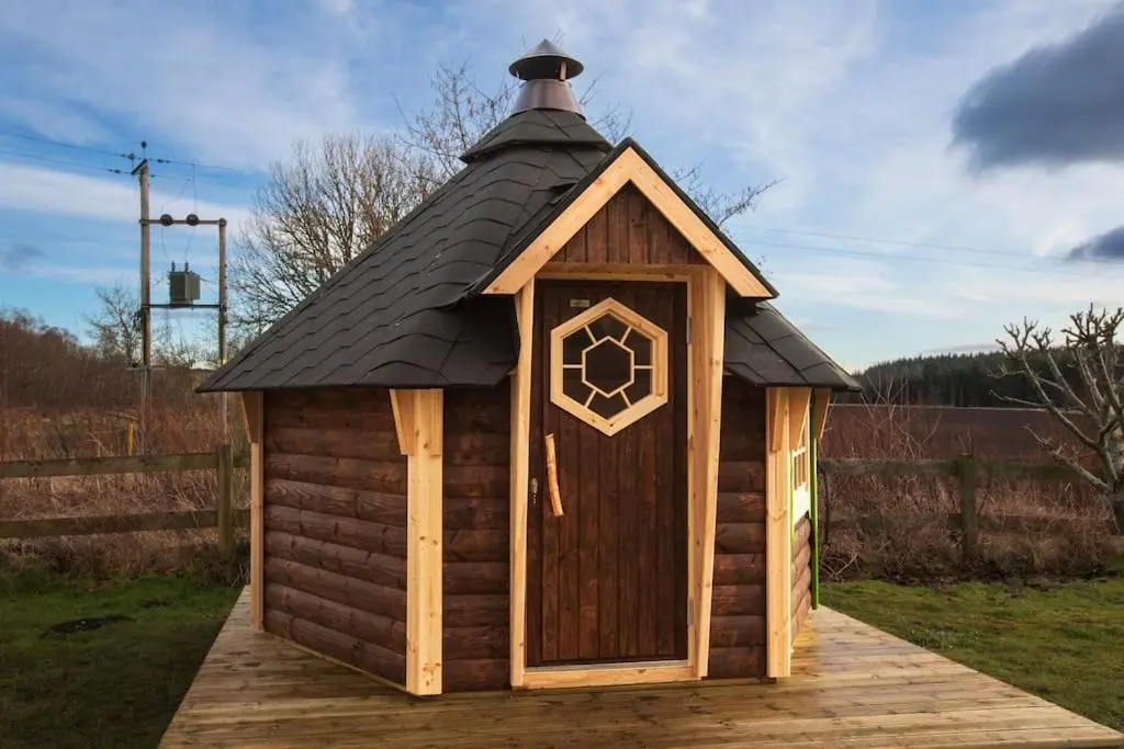 a small wooden dog house with a black roof at Cosy Shepherds Hut with hot tub in the Scottish Highlands in Stittenham