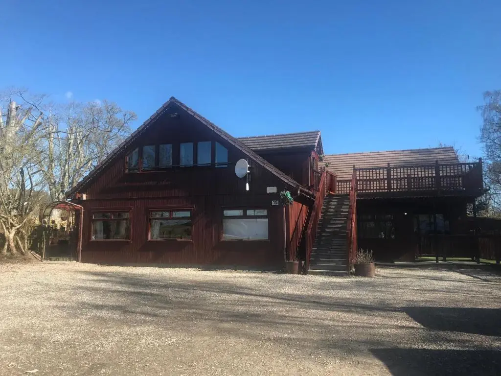 a large wooden house with a staircase in front of it at Kiledinmuir in Tore