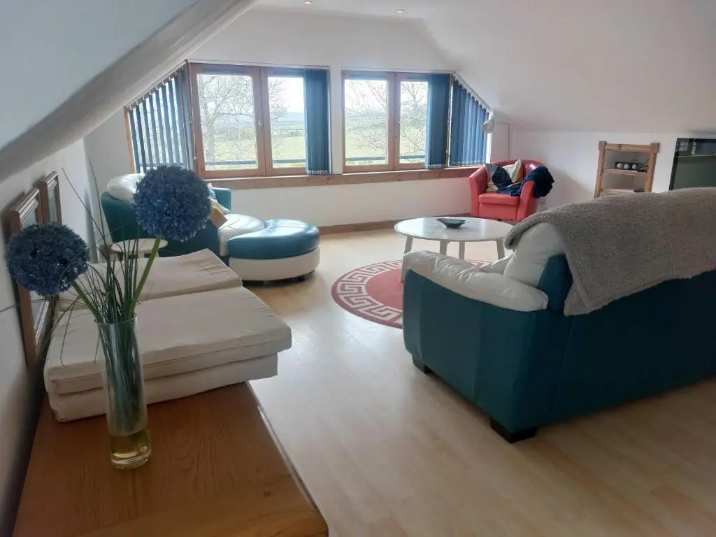a living room with a blue couch and a table at Kiledinmuir in Tore
