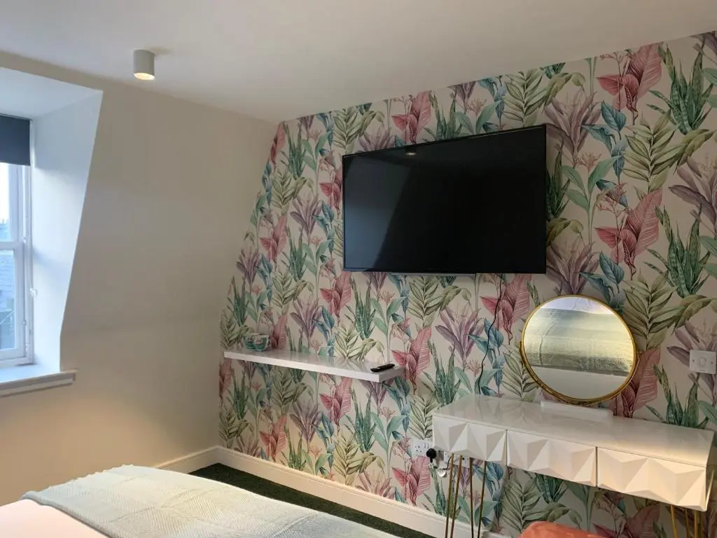 a tv on a wall with a flowery wallpaper at STAG & THISTLE HOTEL AND RESTAURANT in Fraserburgh