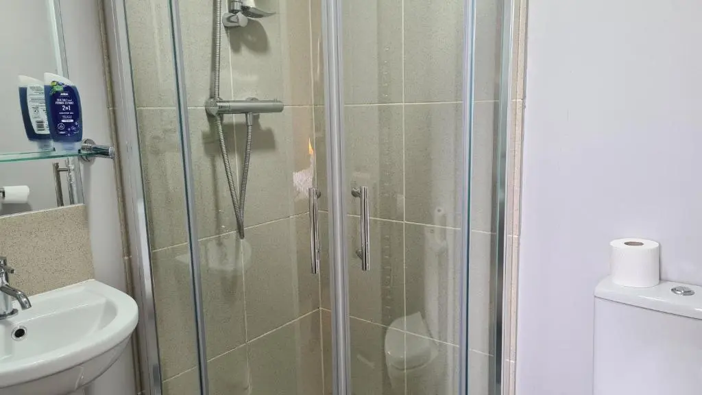 a shower with a glass door next to a sink at Glenisla Hotel in Blairgowrie