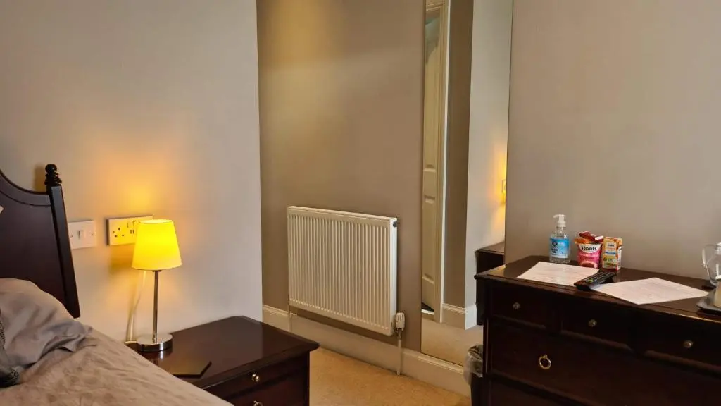 a bedroom with a bed and a dresser and a mirror at Glenisla Hotel in Blairgowrie