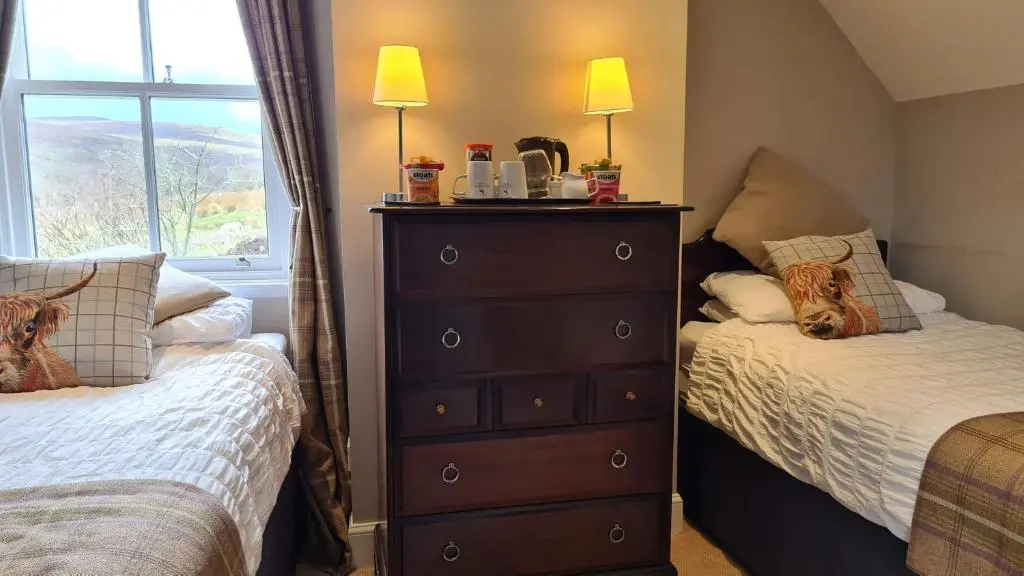 a bedroom with two beds and a dresser with two lamps at Glenisla Hotel in Blairgowrie