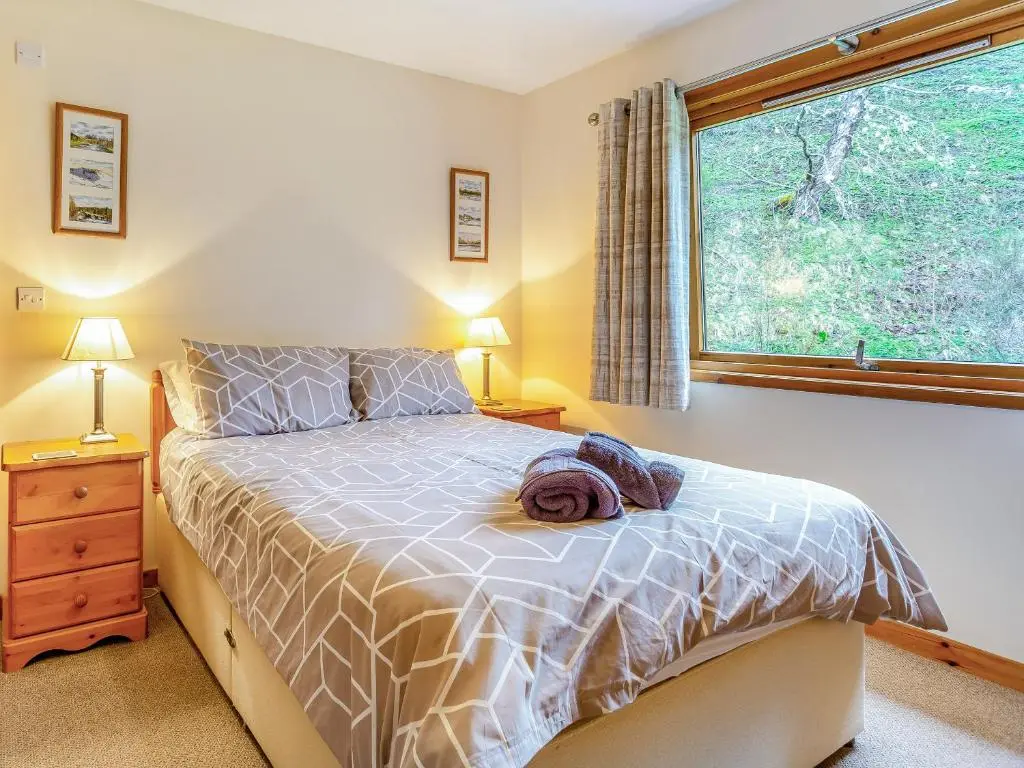 a bedroom with a bed and a window at Balnagowan Mill in Nethy Bridge