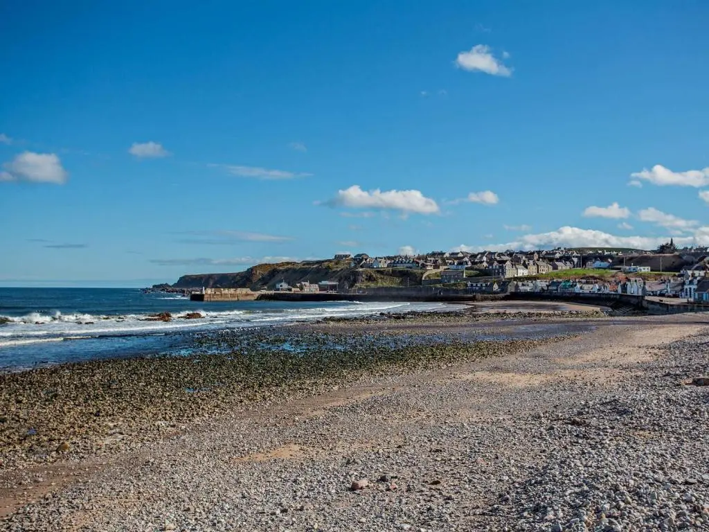 a beach with a rocky shoreline and a town at 1 Bed in Cullen 94536 in Cullen