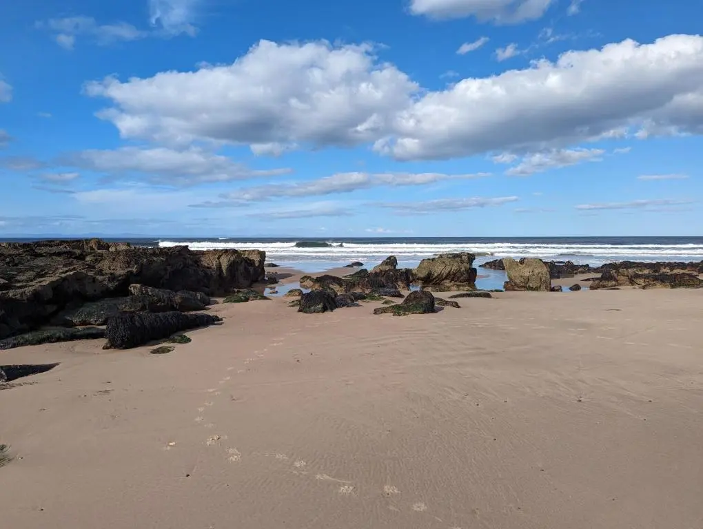 a beach with rocks and the ocean on a cloudy day at D11 - the Dunes at Silver Sands in Lossiemouth
