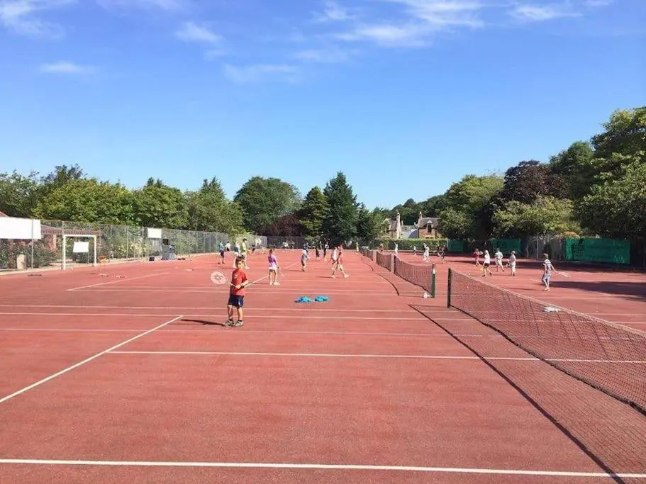 a group of people playing tennis on a tennis court at Heather House, beautiful family home, sleeps 8 in Inverness